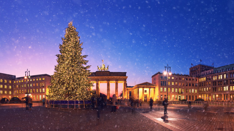 Illuminated Christmas tree and festive decorations in front of Brandenburg Gate during the Christmas season in Berlin, Germany.