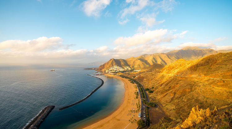 Playa de las Teresitas in Tenerife, Canary Islands, Spain, featuring golden sand beach, calm Atlantic waters protected by a breakwater, and mountain backdrop near Santa Cruz de Tenerife.