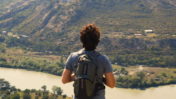 Backpacker enjoying the panoramic view of the Douro River and vineyard-covered hills in northern Portugal.