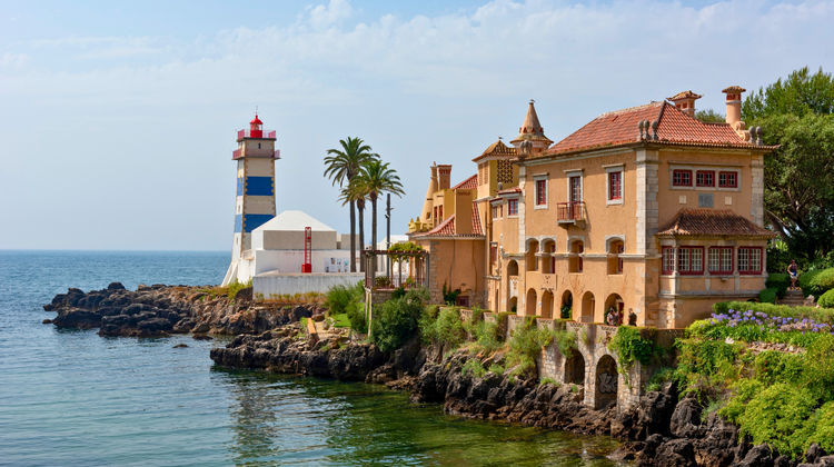 Iconic Santa Marta Lighthouse by the sea in Cascais, Portugal, with traditional Portuguese architecture and rocky coastline