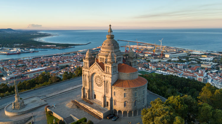Aerial view of Santa Luzia Sanctuary in Viana do Castelo, Portugal, overlooking the city, Lima River, and Atlantic coastline at sunset.