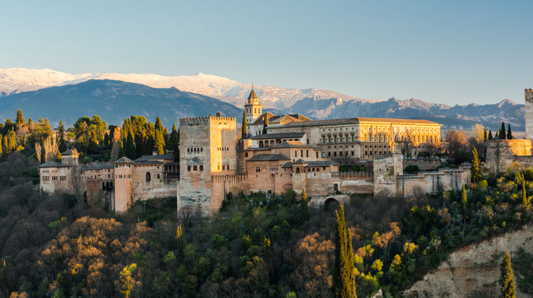 Alhambra Palace in Granada, Spain, with historic fortress walls and towers set against the Sierra Nevada mountains