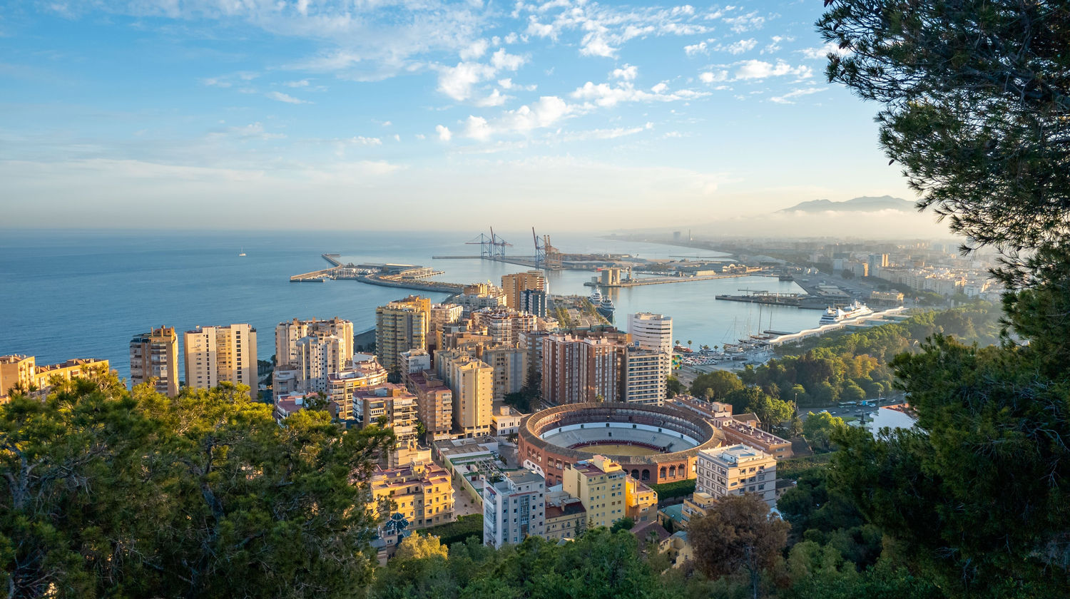 A breathtaking aerial view of Malaga, Spain, featuring the city skyline, Mediterranean coastline, and bustling port.