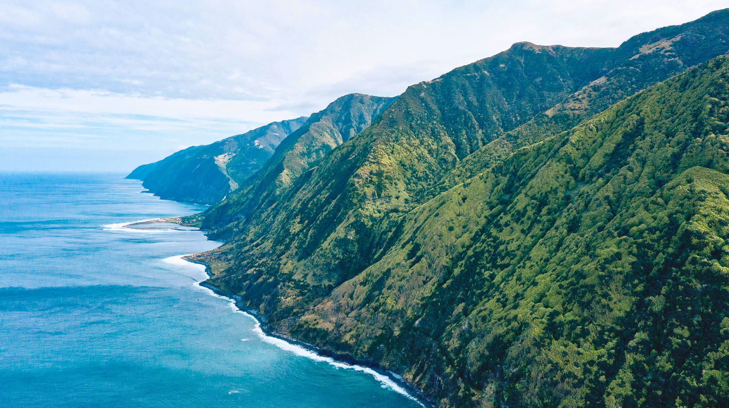 Aerial view of São Jorge Island’s green cliffs dropping into the Atlantic Ocean, showcasing the island’s rugged coastline and natural beauty in the Azores.