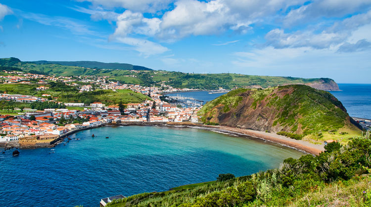 Colorful coastal view of Porto Pim Bay with calm waters and traditional houses on Faial Island in the Azores.