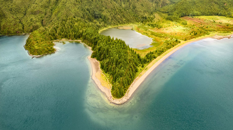 Aerial view of Lagoa do Fogo, a turquoise volcanic crater lake surrounded by lush green mountains on São Miguel Island, Azores, Portugal.