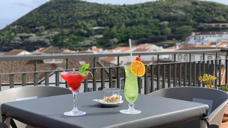 Terraço do hotel Azoris Angra Garden com vista para a cidade e bebidas servidas