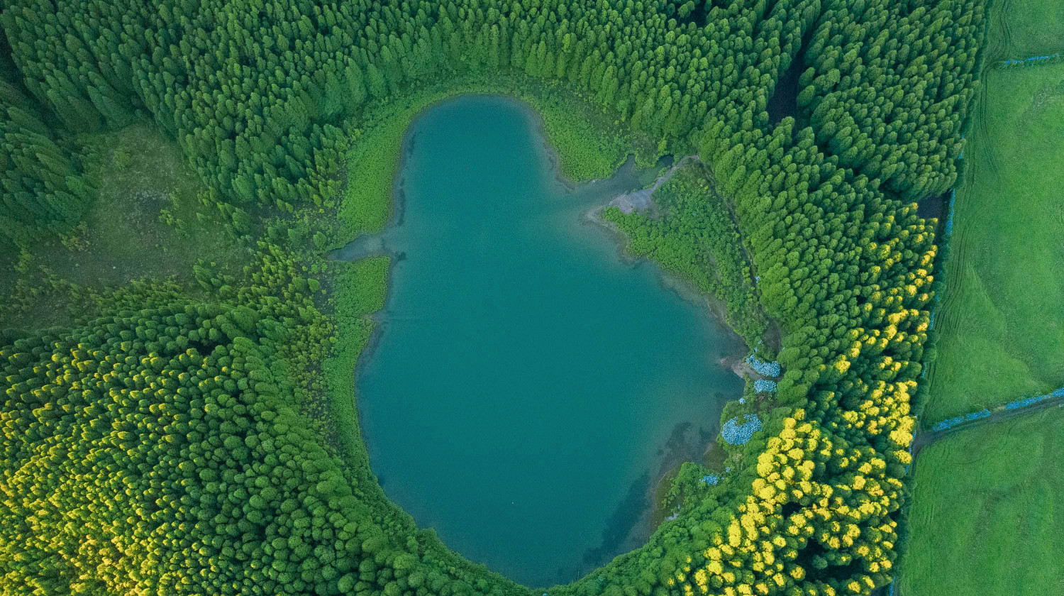 Aerial view of Lagoa do Canário surrounded by dense forest and crater walls
