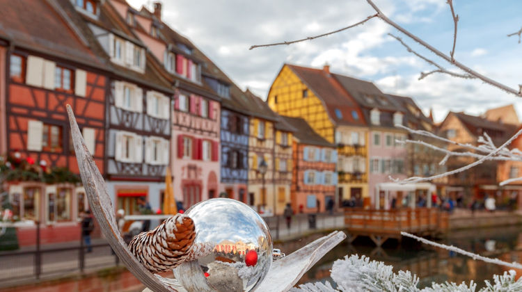 Winter view of the canal and colourful half-timbered houses in the Little Venice district of Colmar, France, with a decorative glass ornament in the foreground