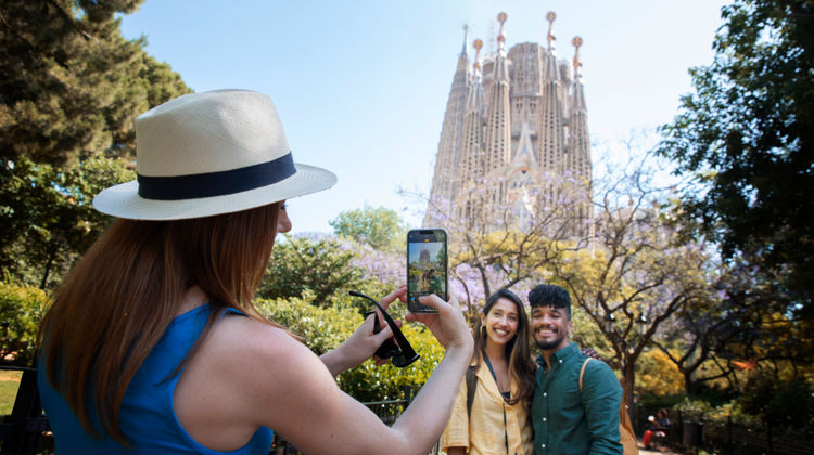 Tourists taking a selfie in front of La Sagrada Família basilica in Barcelona, Spain, designed by Antoni Gaudí.
