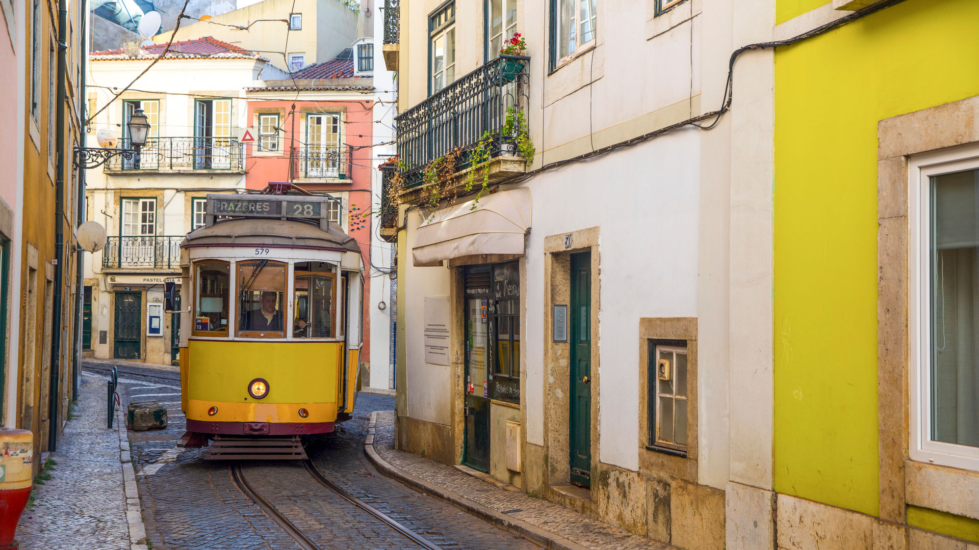 Yellow Tram 28 navigating the narrow, historic streets of Lisbon