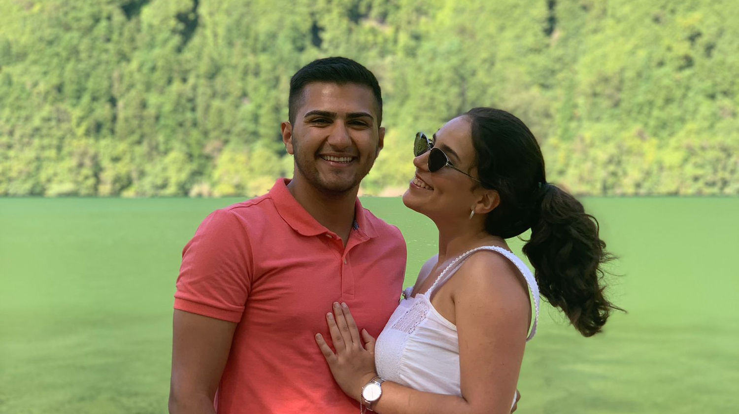 Couple smiling in front of the green waters of Lagoa Verde, surrounded by lush forest in São Miguel Island, Azores.