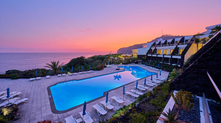 Swimming pool at sunset at Caloura Hotel Resort on São Miguel Island, Azores. The outdoor pool overlooks the coastline, creating a peaceful setting for guests.
