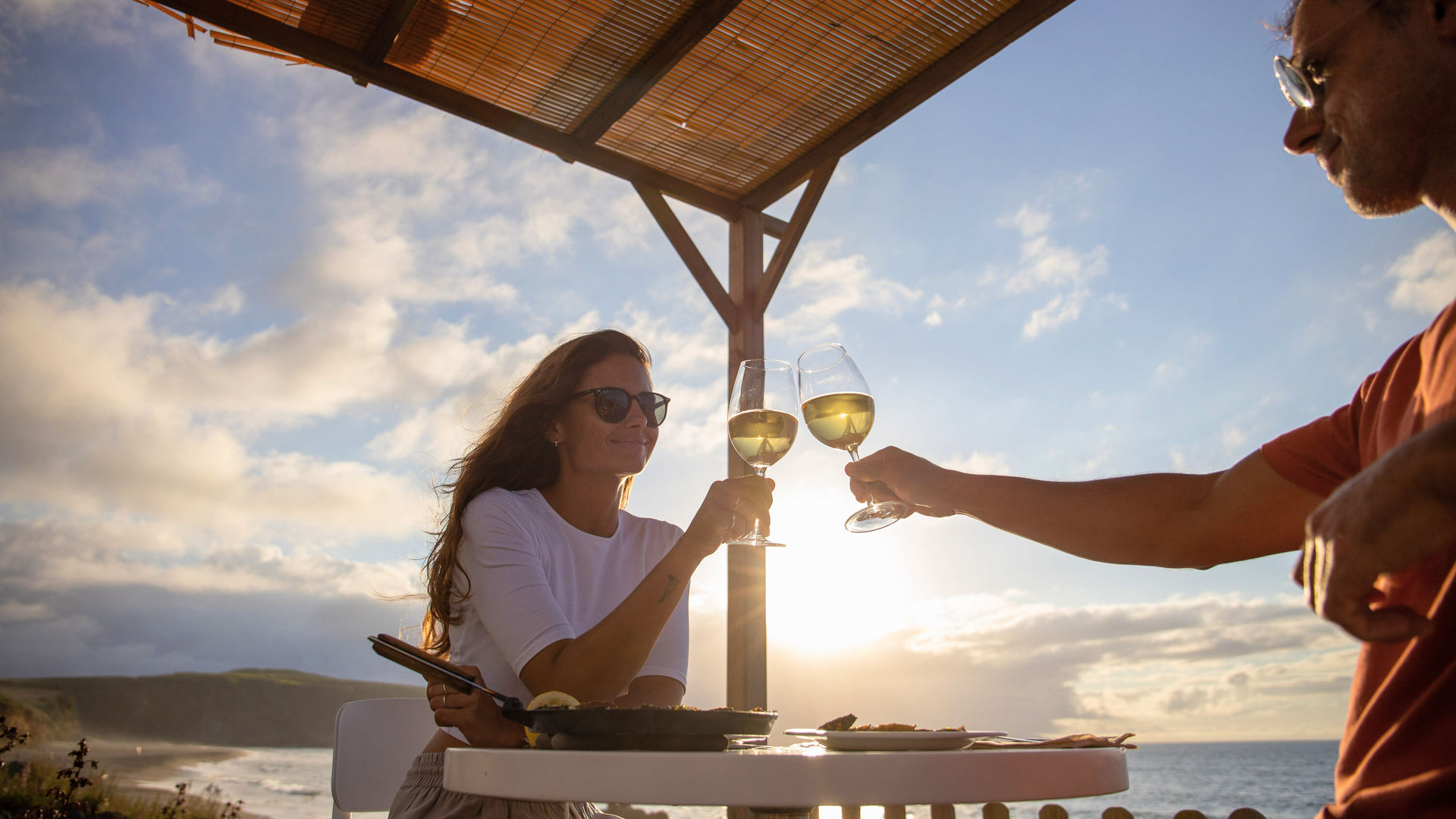 Couple enjoying a sunset wine toast by the ocean in the Azores, part of an all inclusive Azores Getaways experience