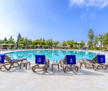 Outdoor swimming pool at Jupiter All-Inclusive Resort in Portugal with sun loungers, blue towels, and refreshing drinks under a clear summer sky