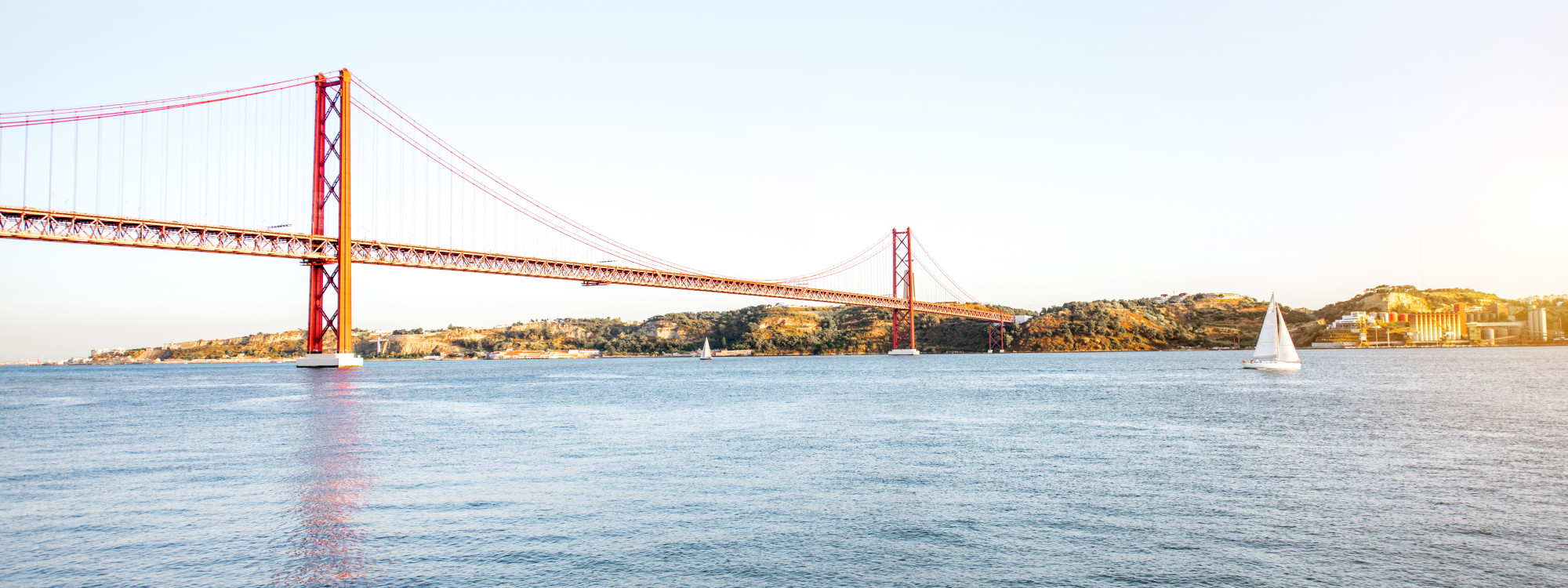 Panoramic view of the 25 de Abril Bridge spanning the Tagus River at golden hour, Lisbon, Portugal