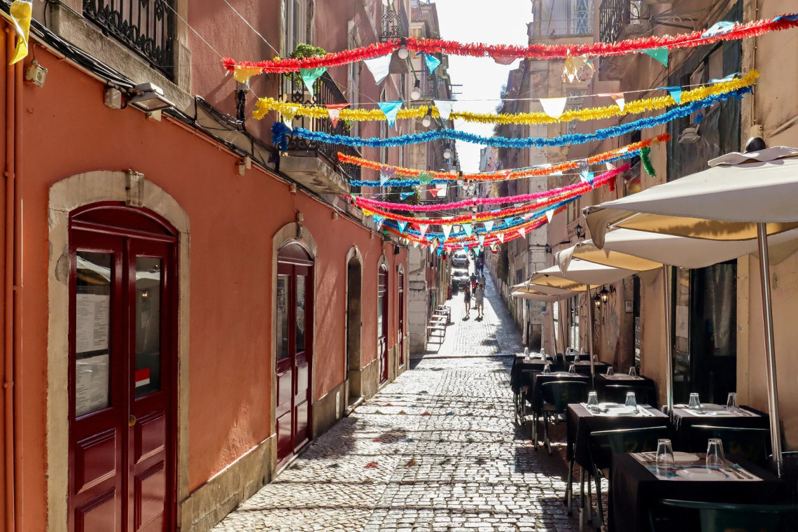 International flags suspended between traditional buildings on a narrow street in Bairro Alto, Lisbon, Portugal