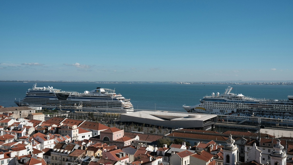 Cruise ships docked at Lisbon Cruise Port along the Tagus River, with the terracotta rooftops and historic buildings of the Alfama district in the foreground.