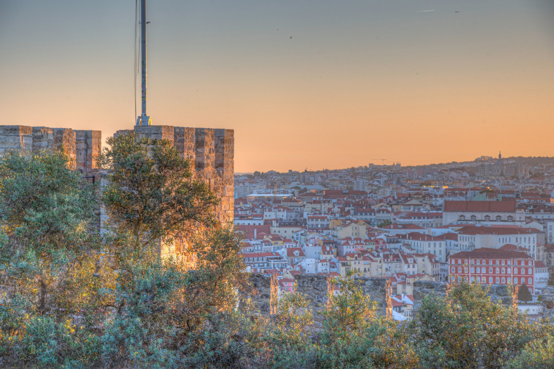 Panoramic sunset view of Lisbon's terracotta rooftops and historic cityscape from the battlements of S&atilde;o Jorge Castle, Portugal