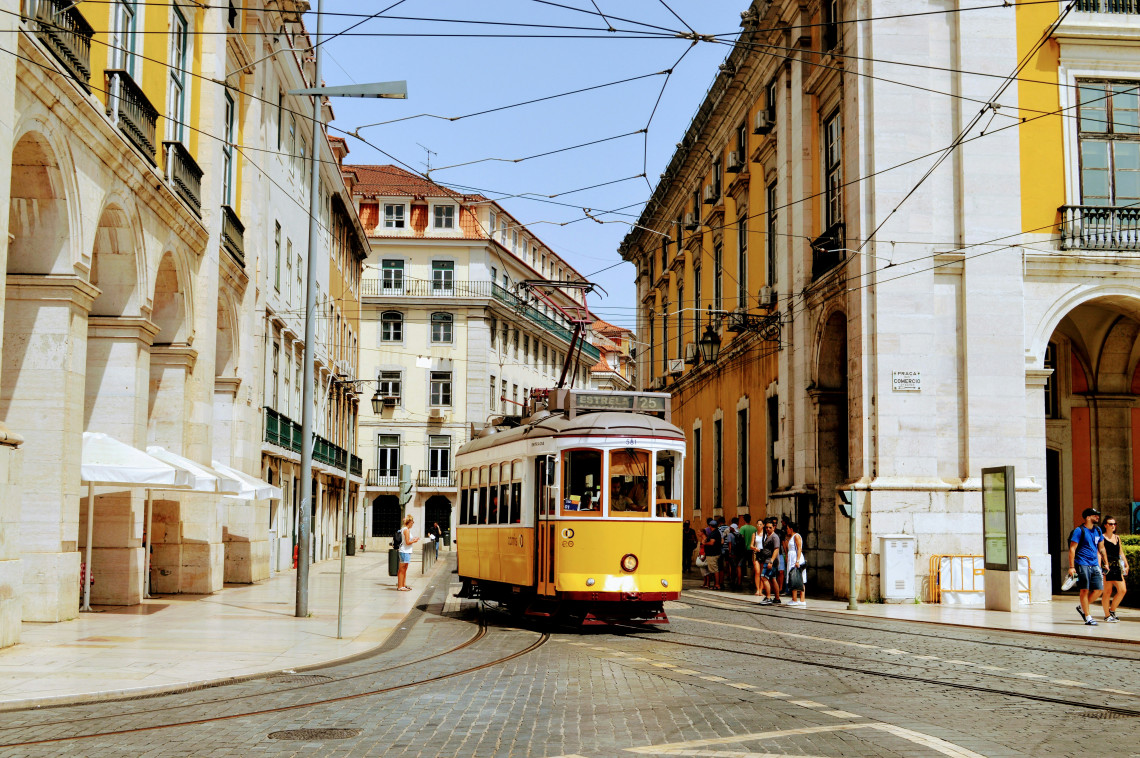 Iconic yellow tram 28 riding through the historic streets of Baixa Chiado in Lisbon, Portugal, surrounded by elegant Pombaline buildings on a sunny day