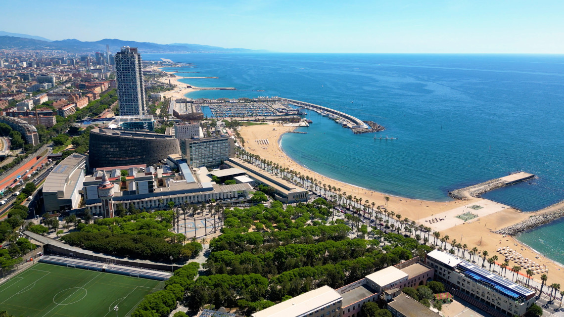Aerial view of Barceloneta Beach and Port Ol&iacute;mpic in Barcelona, Spain, with sandy beaches, marina facilities and the Mediterranean Sea extending along the city coastline.