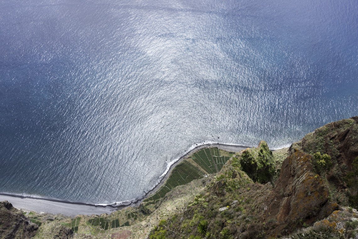 A view from Cabo Gir&atilde;o Viewpoint in C&acirc;mara de Lobos, Madeira Island, Portugal, looking down over steep coastal cliffs, small cultivated terraces, and the Atlantic Ocean. The image shows Madeira&rsquo;s dramatic cliff landscape from one of the island&rsquo;s highest viewpoints.