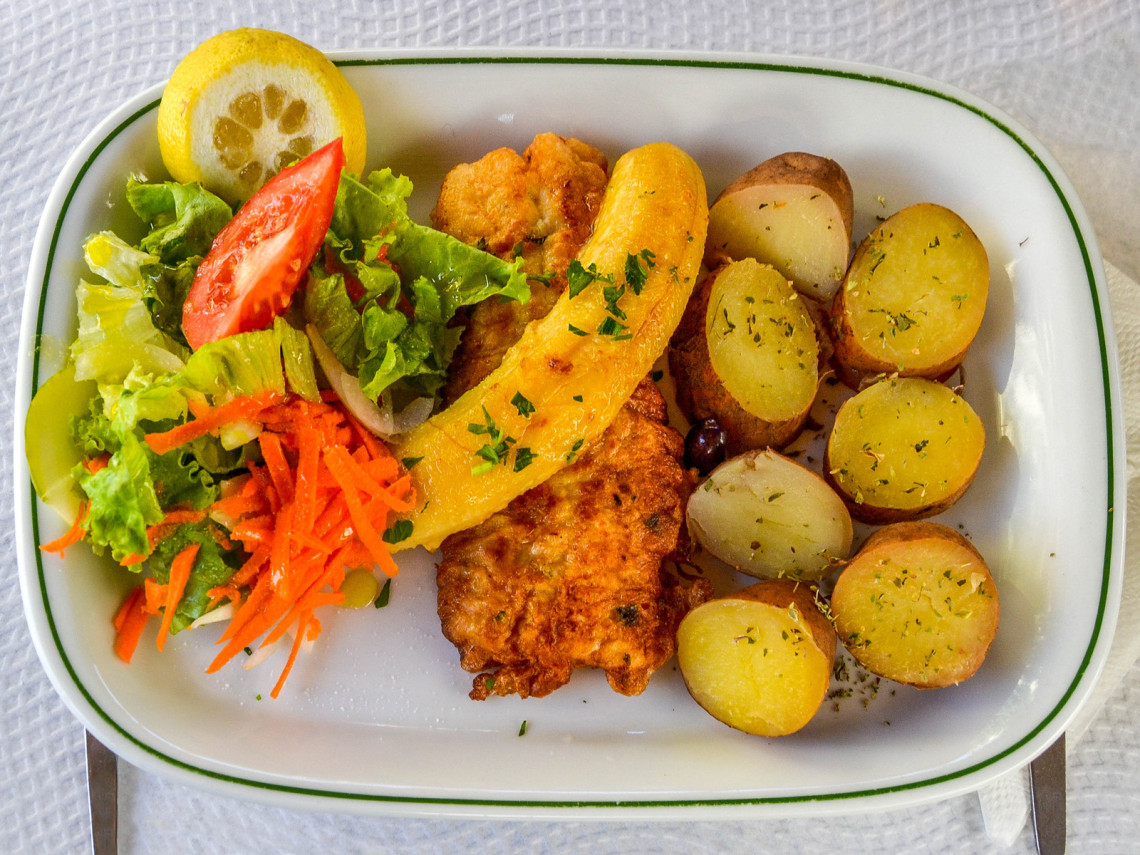 Espada com Banana from Madeira Island, Portugal, served with fried black scabbardfish, banana, potatoes, and salad. The image shows a traditional Madeiran seafood dish commonly found in local restaurants.