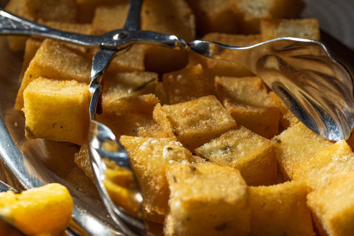 Milho Frito from Madeira Island, Portugal, served as golden fried cornmeal cubes with a crisp exterior. The image shows a traditional Madeiran side dish often served with espetada and local meals.
