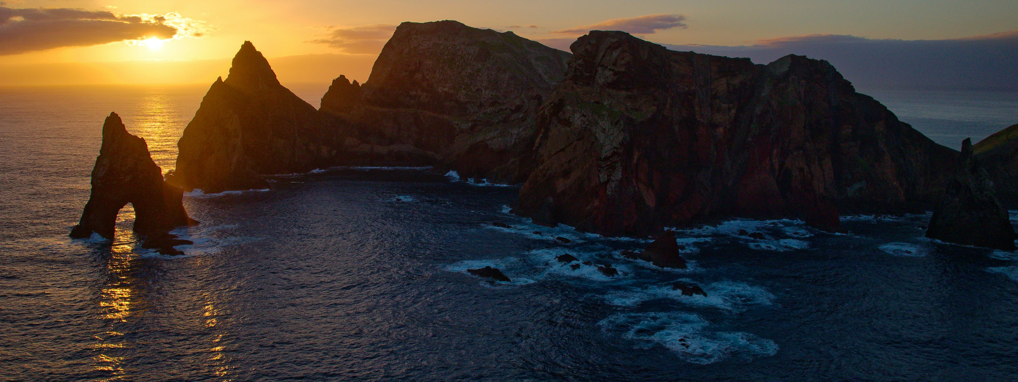 Sunset over Ponta de São Lourenço on Madeira Island, showing rugged volcanic cliffs, offshore rock formations and the Atlantic Ocean.