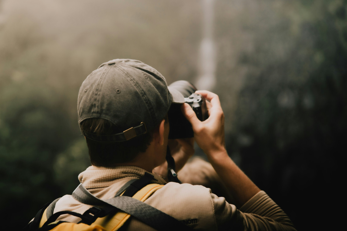 Photographer exploring Madeira&rsquo;s Laurisilva forest, surrounded by dense subtropical vegetation and the island&rsquo;s lush mountain landscape.