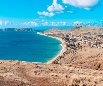 Panoramic view of Porto Santo Beach in Vila Baleira, Porto Santo, Portugal, showing the island’s long golden sand beach, turquoise Atlantic waters, and the town stretching along the coastline. The elevated viewpoint highlights one of Portugal’s most disti