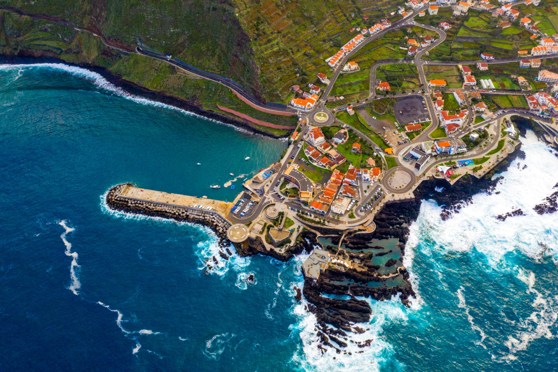 Aerial view of Porto Moniz, a coastal town in Madeira with a harbor jetty and volcanic rock formations