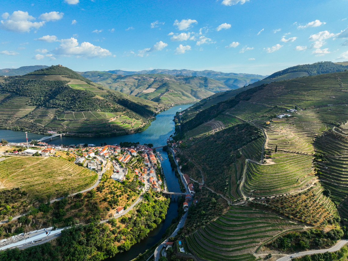 Aerial view of Pinh&atilde;o village where a river meets the Douro, surrounded by terraced vineyard hillsides