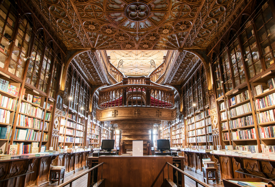 Interior view of Livraria Lello in Porto, Portugal, showing its carved wooden staircase, detailed ceiling, and book-lined galleries. The image highlights one of Porto&rsquo;s most famous historic bookstores.