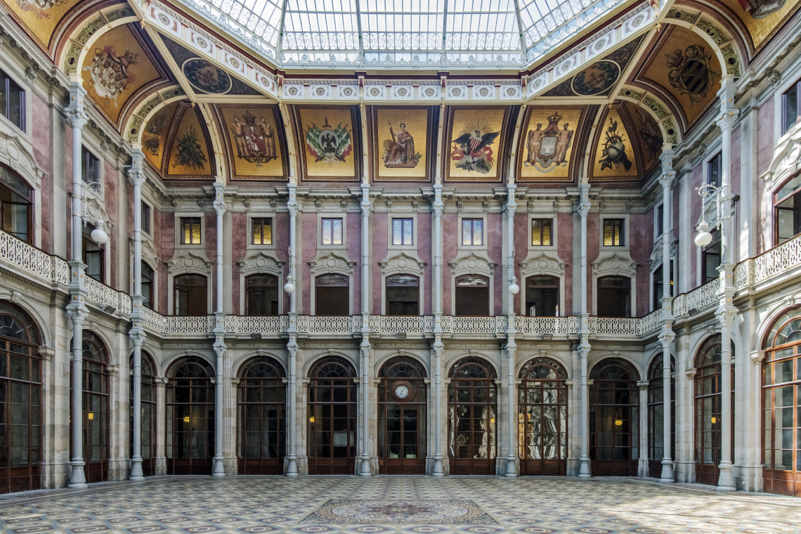 Interior view of Pal&aacute;cio da Bolsa in Porto, Portugal, showing the P&aacute;tio das Na&ccedil;&otilde;es with its glass roof, decorative panels, and historic architectural details. The building is one of Porto&rsquo;s key cultural and heritage landmarks.
