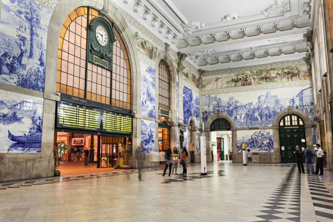 Interior view of S&atilde;o Bento Station in Porto, Portugal, showing its main hall lined with blue and white azulejo tile panels. The image highlights one of Porto&rsquo;s most visited railway landmarks and its detailed tile artwork.