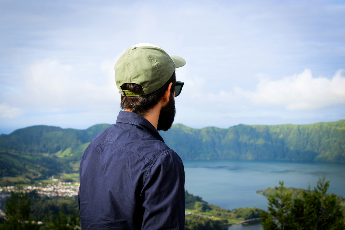 Traveller standing at a viewpoint overlooking the Sete Cidades twin crater lakes and volcanic caldera, S&atilde;o Miguel Island, Azores