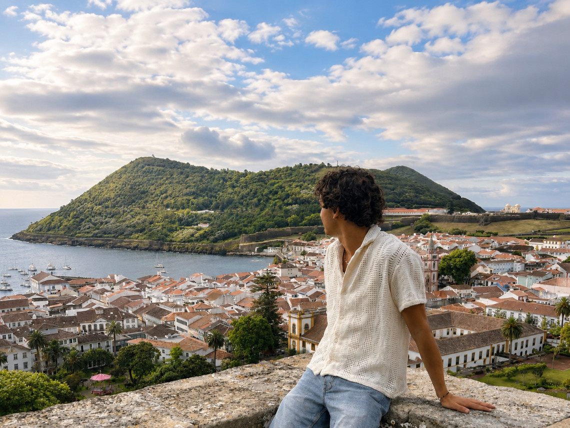 Traveler overlooking Angra do Hero&iacute;smo from Alto da Mem&oacute;ria, with the historic city&rsquo;s red rooftops, sheltered bay and forested Monte Brasil filling the panorama.