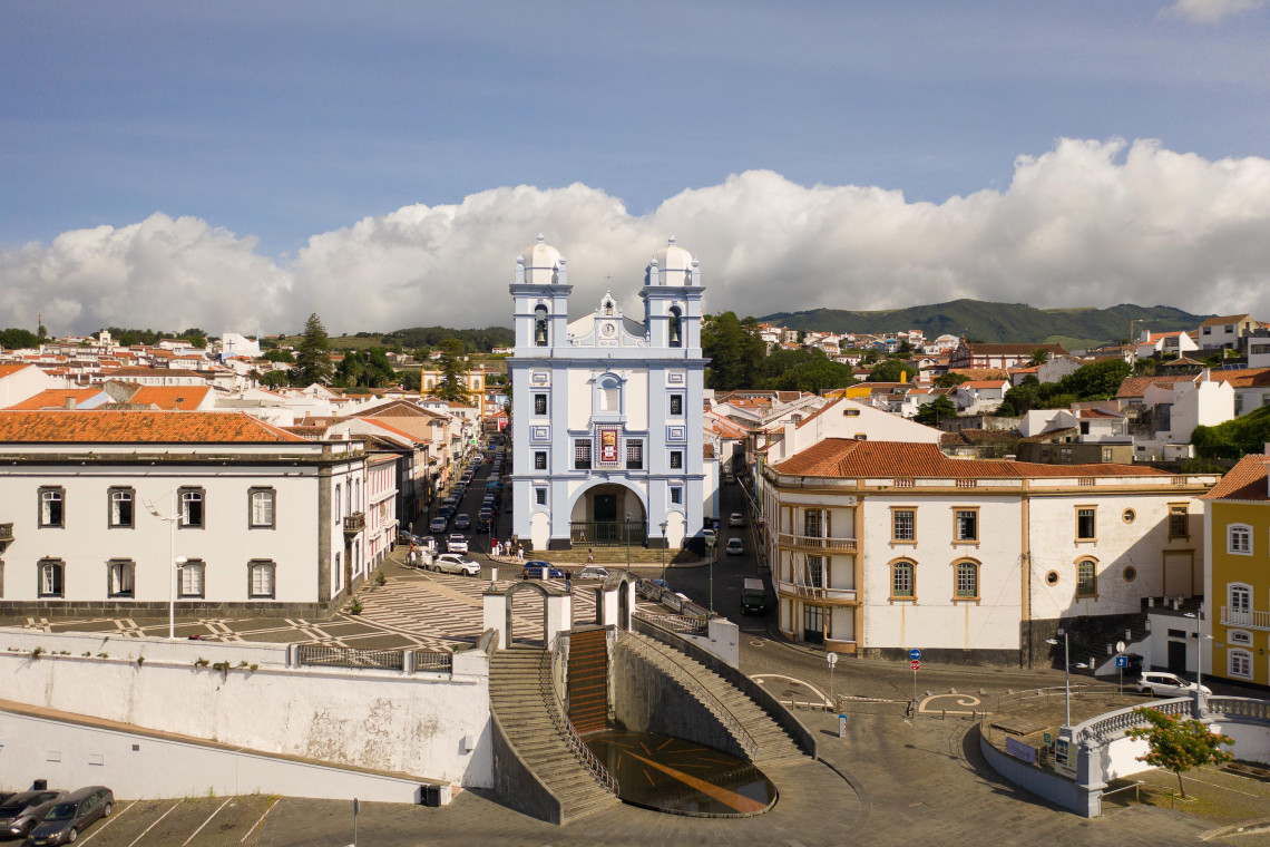 Igreja da Miseric&oacute;rdia in the historic center of Angra do Hero&iacute;smo, with its blue-and-white fa&ccedil;ade and twin bell towers rising above the surrounding red-roofed streets.