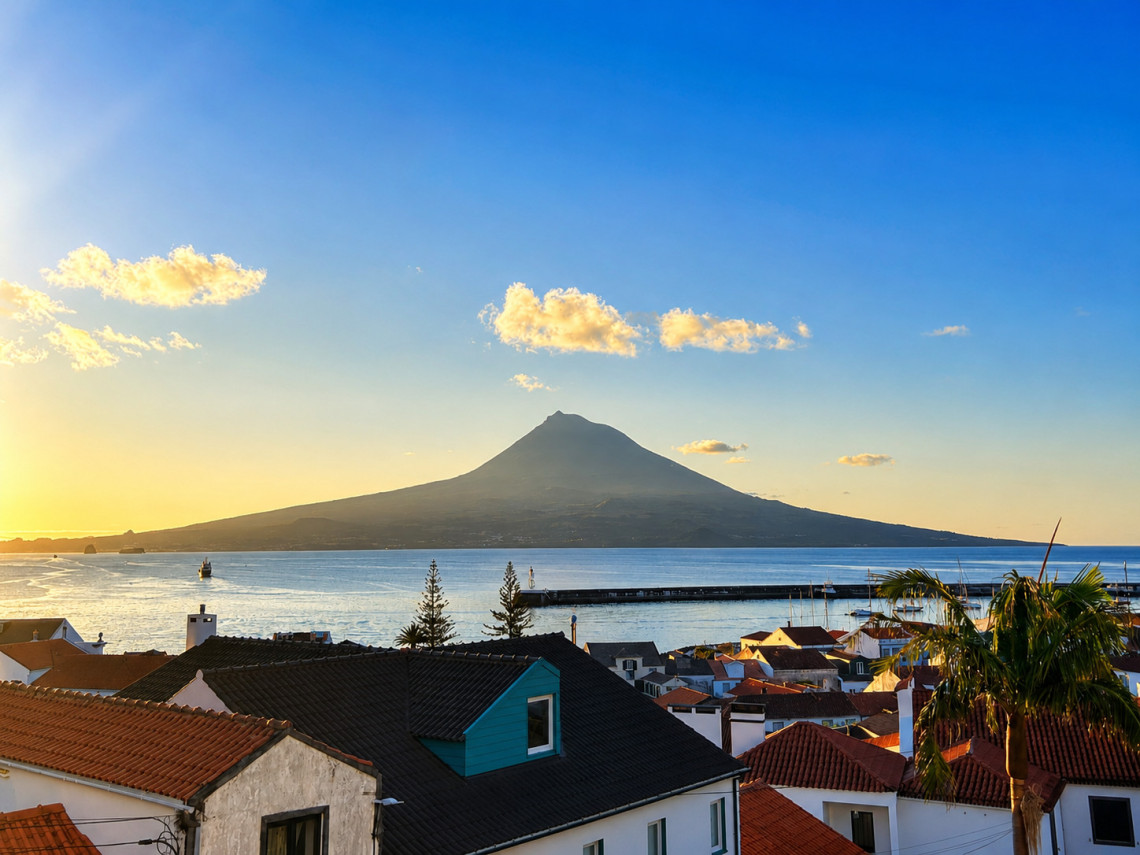 Panoramic view of Mount Pico from Madalena on Pico Island, Azores, Portugal. Portugal's highest mountain rises above the Atlantic Ocean, overlooking the town's red-roofed houses and waterfront.