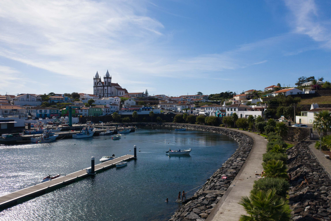 View over the harbour and coastal village of S&atilde;o Mateus da Calheta on Terceira Island, with small fishing boats, traditional houses and the parish church overlooking the waterfront.