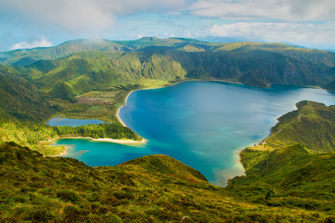 Panoramic view of Lagoa do Fogo on S&atilde;o Miguel Island, showing the blue volcanic crater lake, green caldera slopes and smaller lagoons along the shoreline.