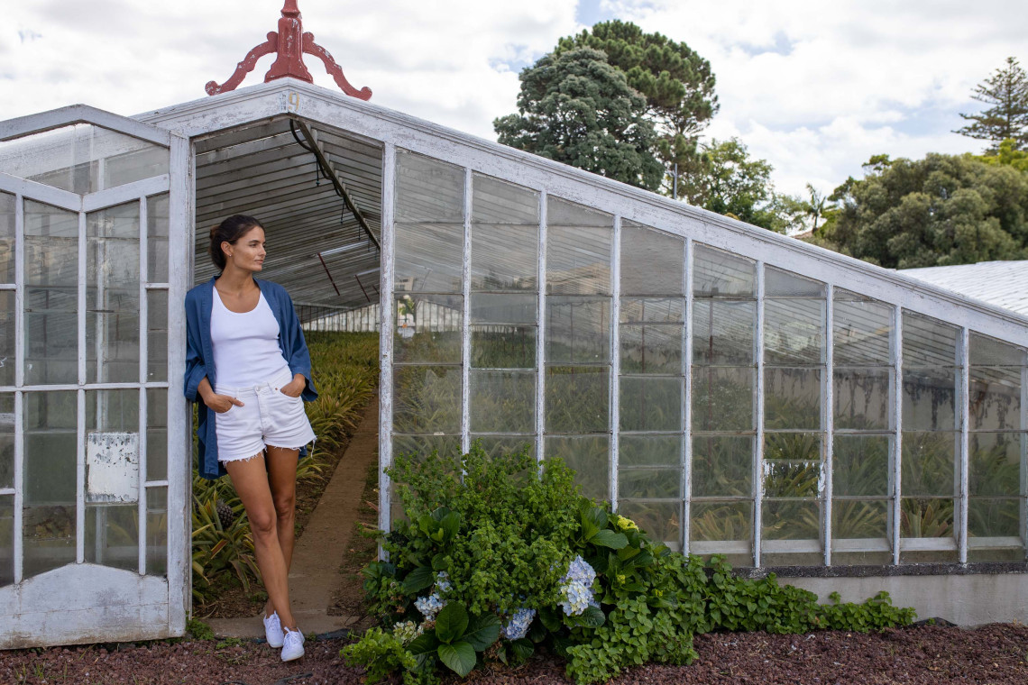 Visitor exploring a traditional glass pineapple greenhouse in Ponta Delgada, where Anan&aacute;s dos A&ccedil;ores is cultivated on S&atilde;o Miguel Island.