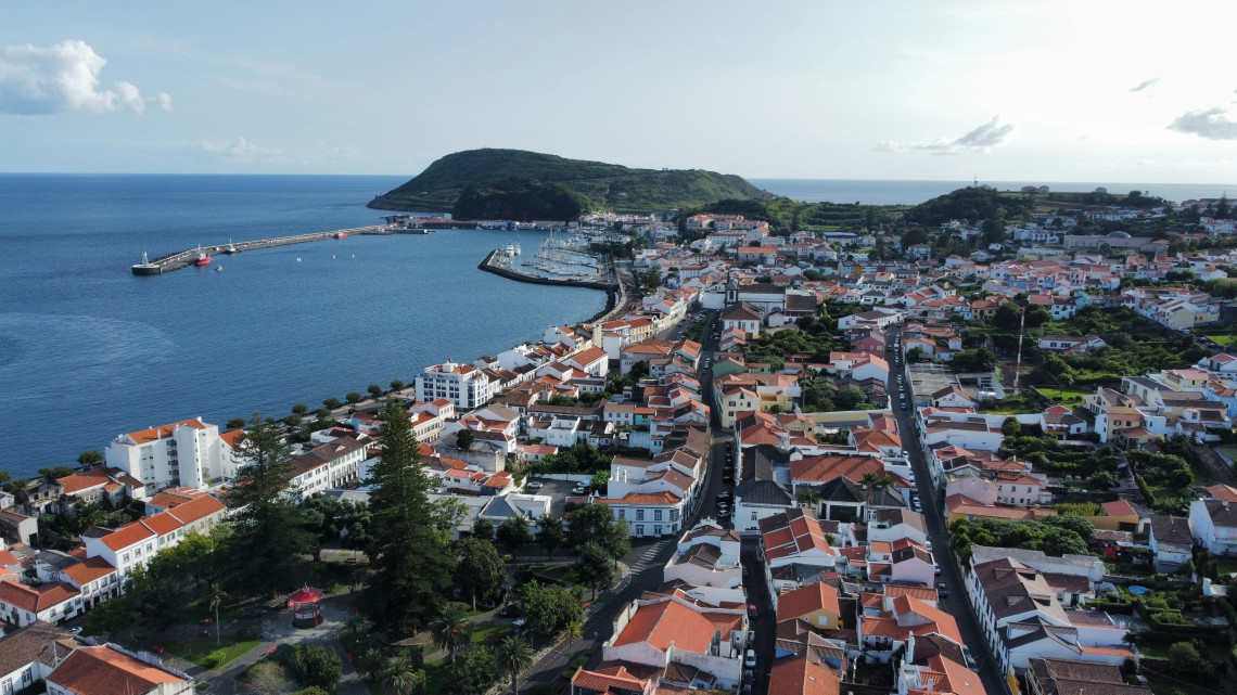 Aerial view of a coastal town with red roof houses and harbor on an Azores island, showing local infrastructure and community setting