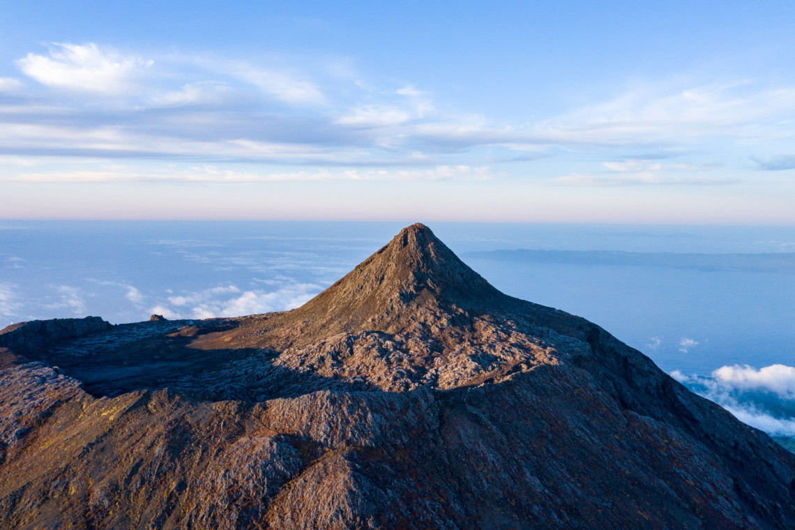 Close view of the rocky volcanic summit of Mount Pico, Portugal's highest mountain, rising above the clouds on Pico Island in the Azores.