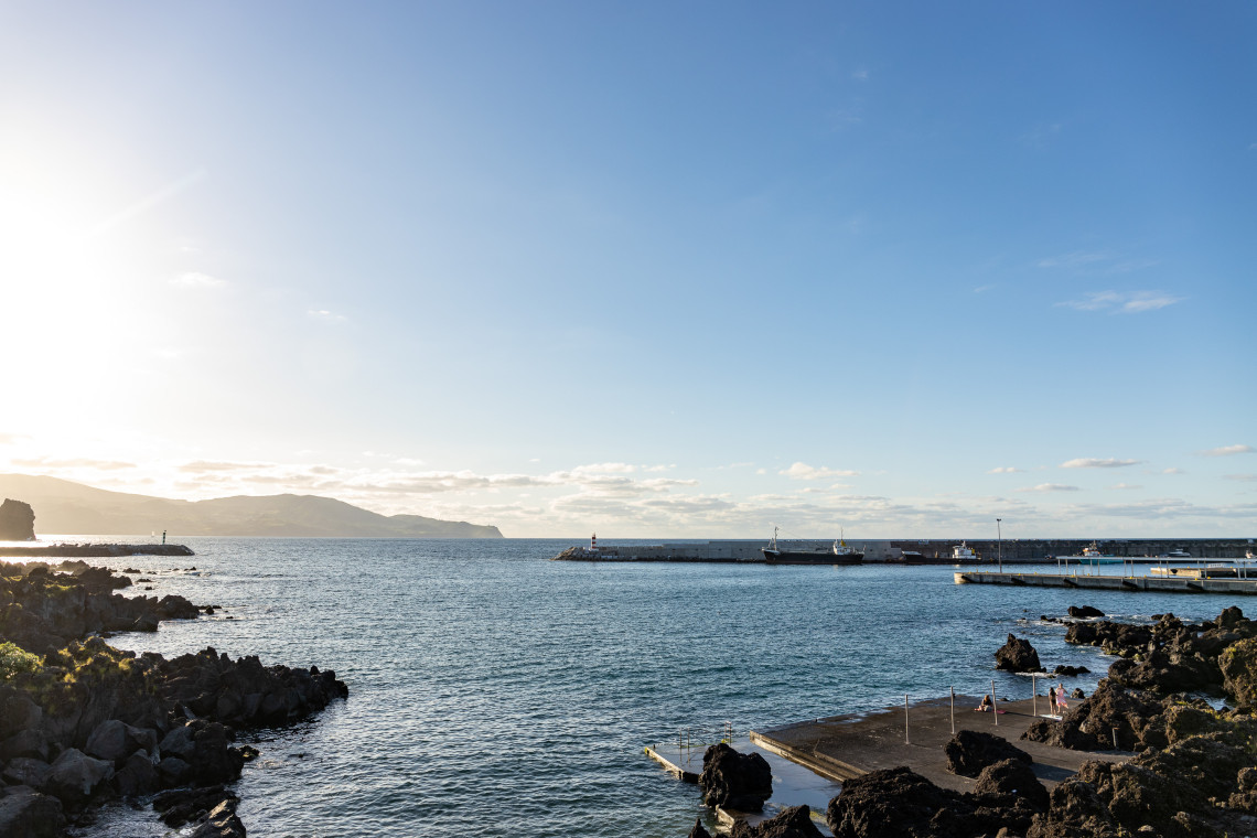 Natural lava rock pools at Madalena with calm clear Atlantic water and views across the channel to Faial Island at sunset, Pico Island, Azores