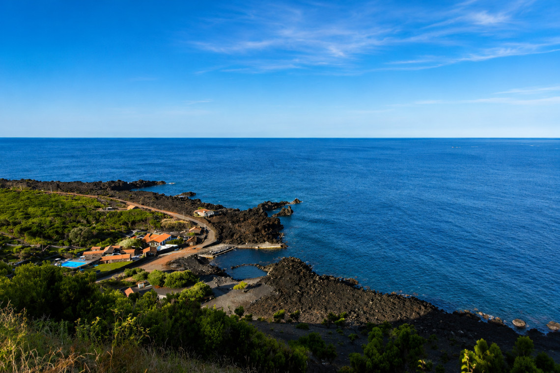 Elevated view of Pocinho in Candel&aacute;ria on Pico Island, showing a small coastal swimming area surrounded by black volcanic rock and the Atlantic Ocean.