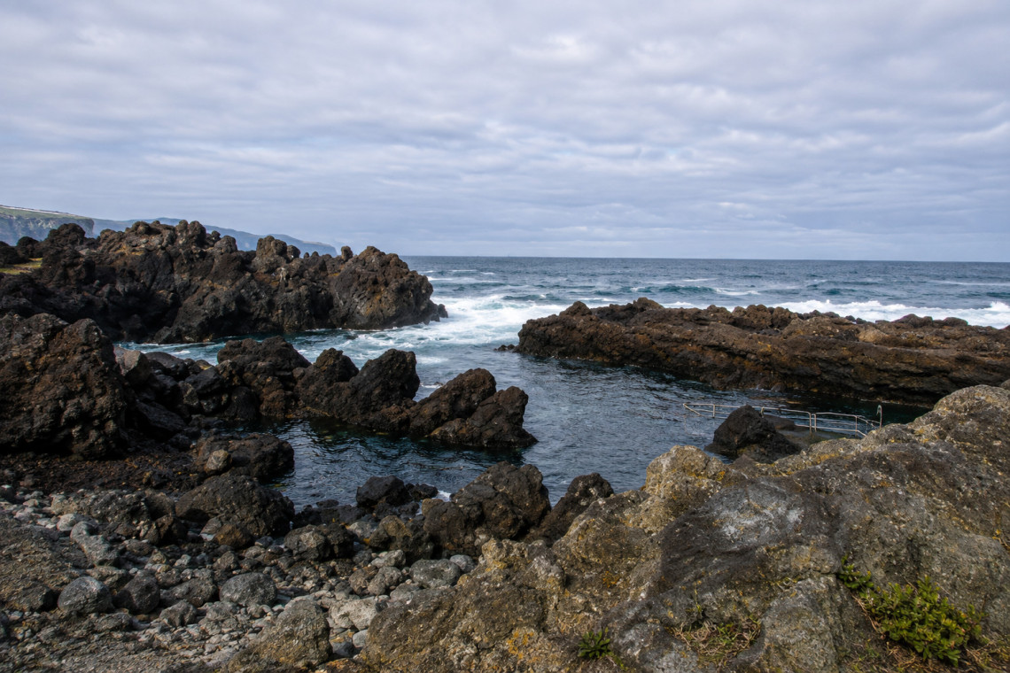 Formosinha bathing area in Toledos on Pico Island, where clear Atlantic water meets rugged black volcanic rock formations along the coast.