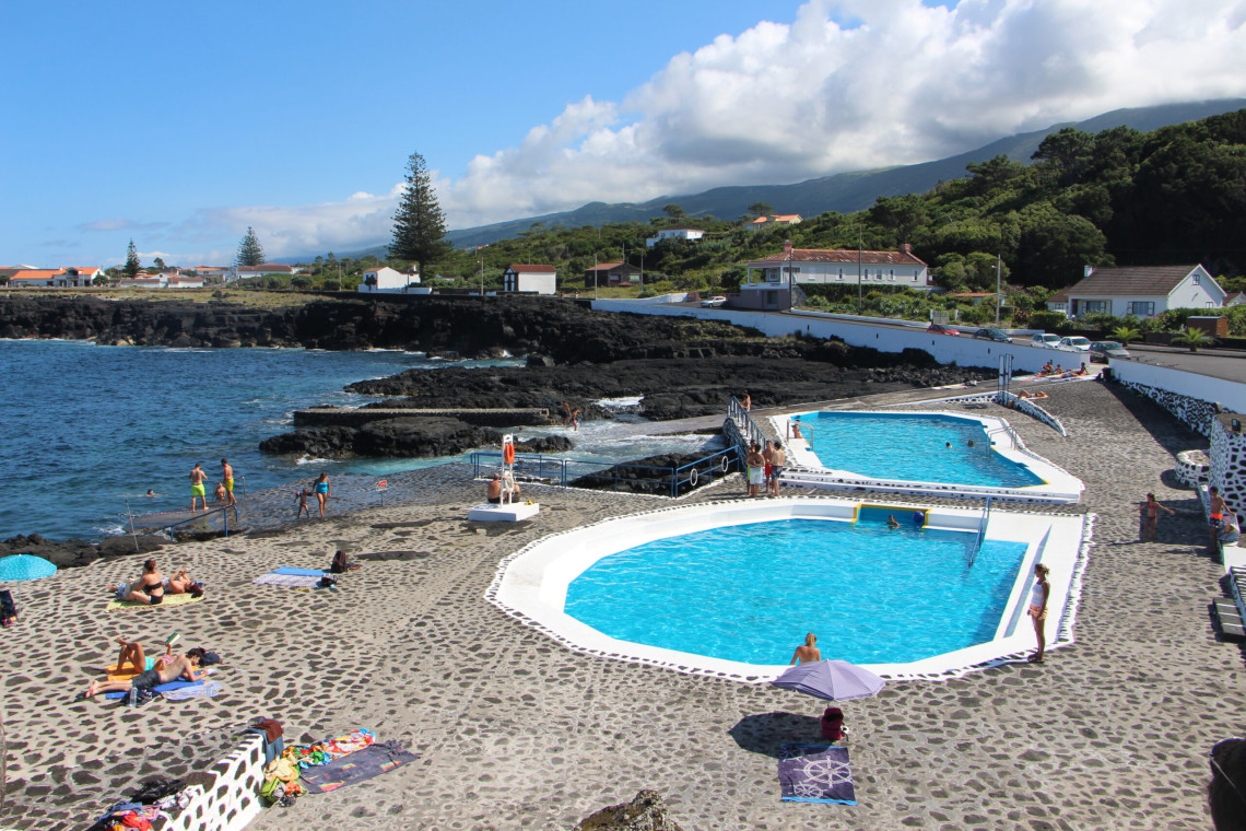 Piscinas de Santo Ant&oacute;nio on Pico Island, featuring maintained seawater swimming pools beside the volcanic shoreline. Paved sunbathing areas and direct ocean access surround the pools.