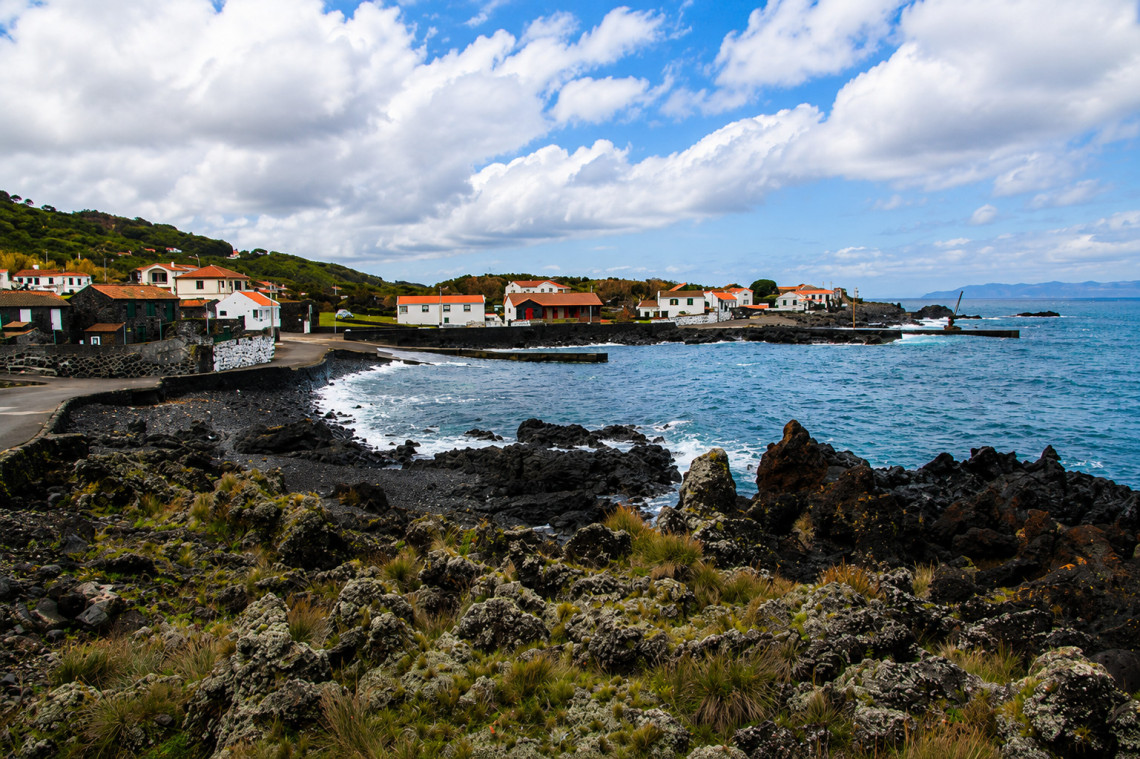 Prainha do Norte on Pico Island, with a dark volcanic shoreline, black lava formations and traditional houses facing the Atlantic Ocean in the parish of Prainha.